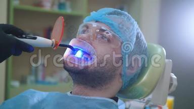 医生和病人在牙科办公室用拉钩，用紫外线和橙色保护屏清洁